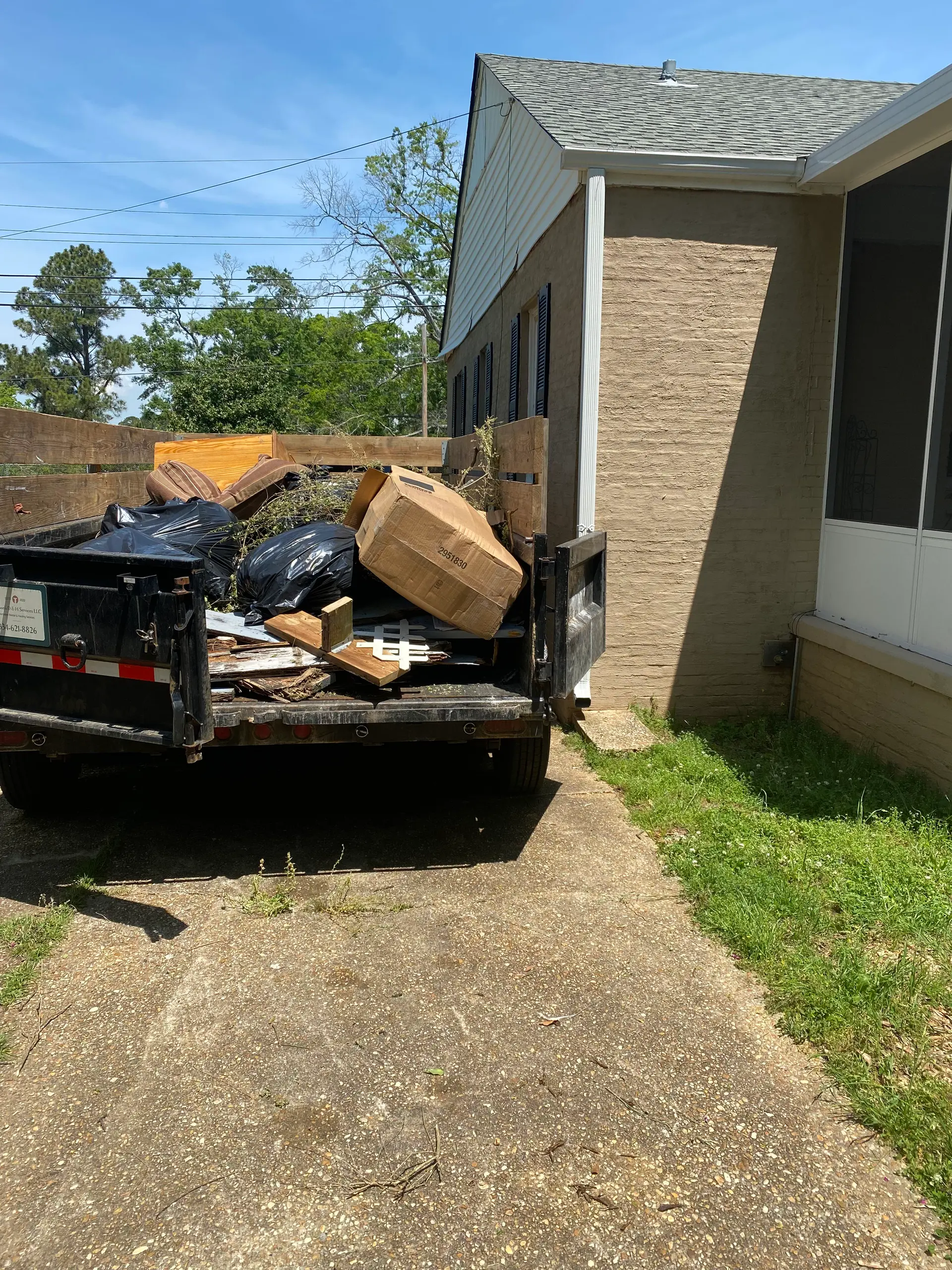 Melanin Site Solutions dump trailer loaded with household junk beside a Montgomery home