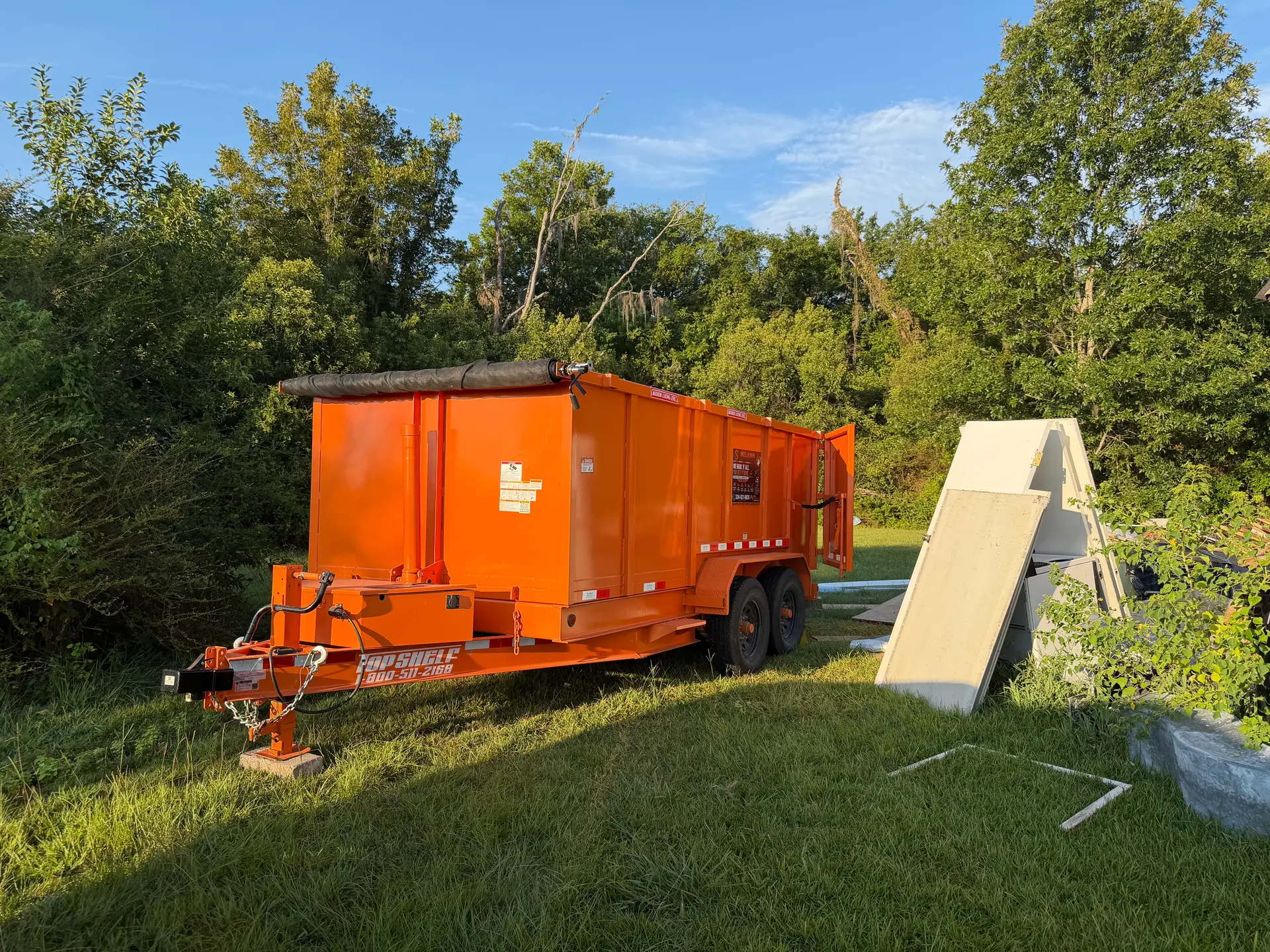 SiteTub dumpster staged on a grassy job site at golden hour